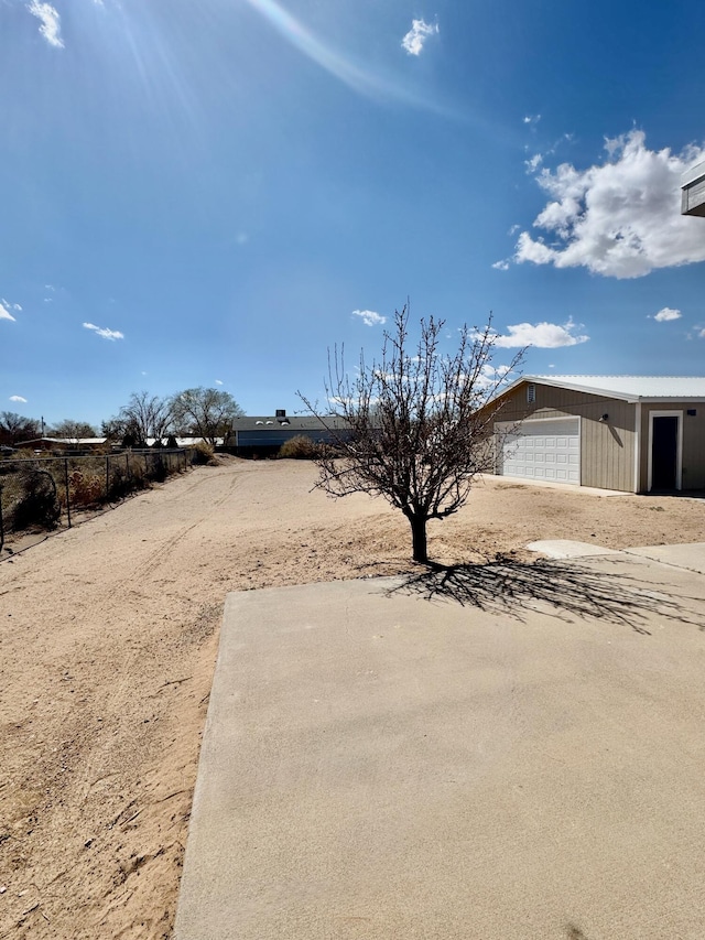 view of yard with a garage and dirt driveway