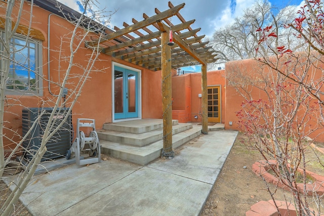 property entrance with french doors, a pergola, and stucco siding