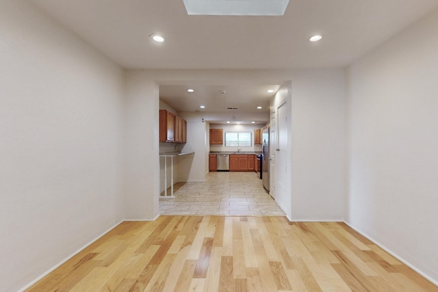 kitchen with brown cabinets, light wood-style flooring, open floor plan, recessed lighting, and dishwasher