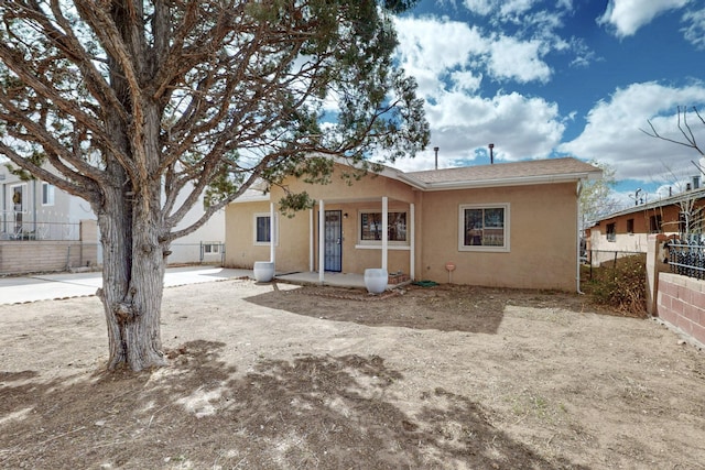 back of property featuring fence and stucco siding