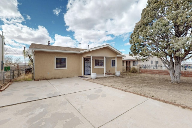 view of front of property featuring stucco siding, a patio area, and fence