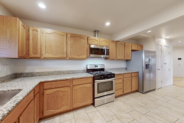 kitchen with a sink, light stone counters, recessed lighting, and stainless steel appliances