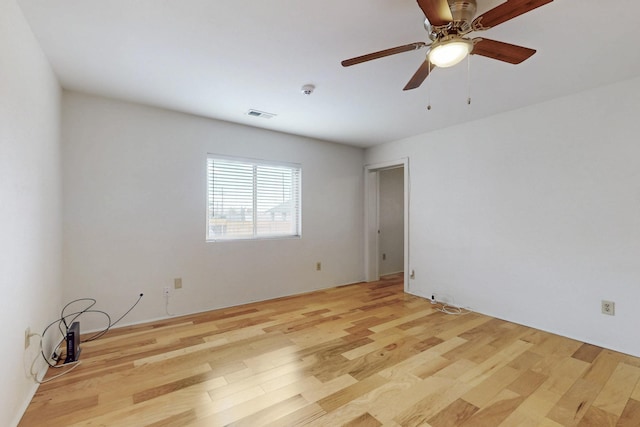 empty room featuring visible vents, light wood-style flooring, and ceiling fan