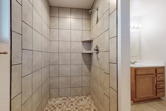 bathroom with a tile shower, tile patterned flooring, and vanity