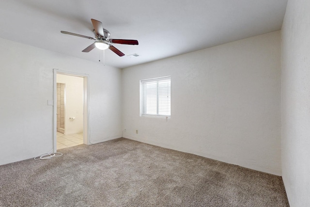 spare room with visible vents, light colored carpet, and a ceiling fan