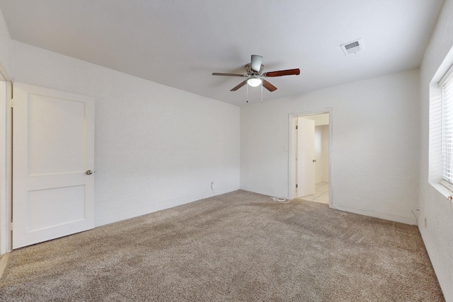 spare room with visible vents, light carpet, and a ceiling fan