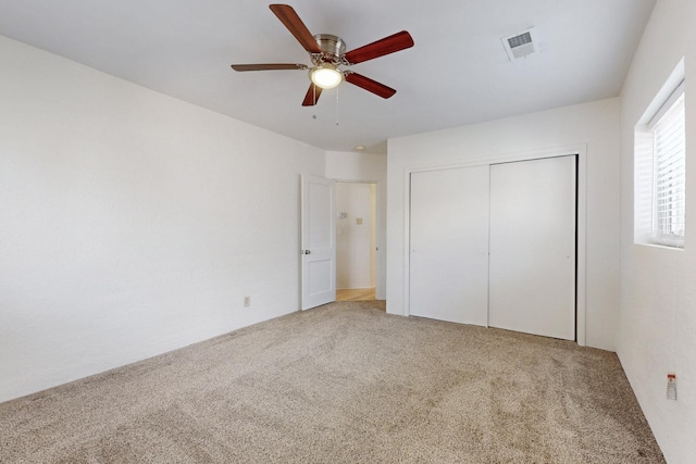 unfurnished bedroom featuring visible vents, light carpet, a closet, and ceiling fan