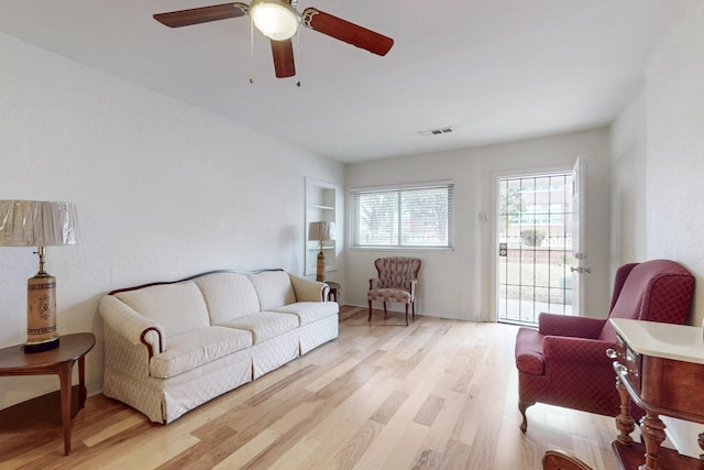 living area featuring a ceiling fan, visible vents, and light wood-type flooring