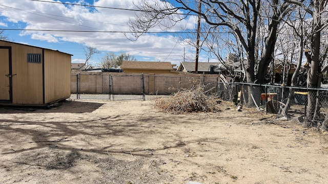 view of yard featuring a gate, a storage shed, an outdoor structure, and fence