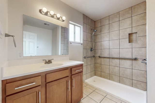 full bath featuring vanity, tile patterned flooring, visible vents, and a tile shower