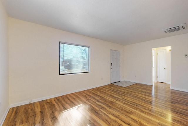 empty room featuring visible vents, baseboards, and wood finished floors