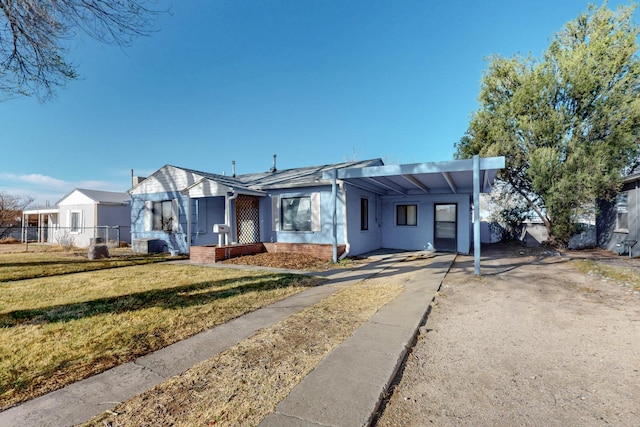 view of front facade with a front lawn, an attached carport, fence, concrete driveway, and brick siding