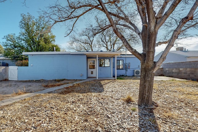 view of front facade with concrete block siding, ac unit, a gate, and fence