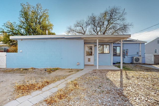 exterior space with ac unit, a gate, concrete block siding, and fence