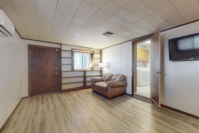 sitting room with visible vents, washer / dryer, light wood-style flooring, and an AC wall unit