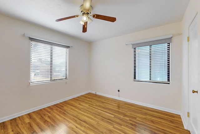 spare room featuring light wood finished floors, a ceiling fan, and baseboards