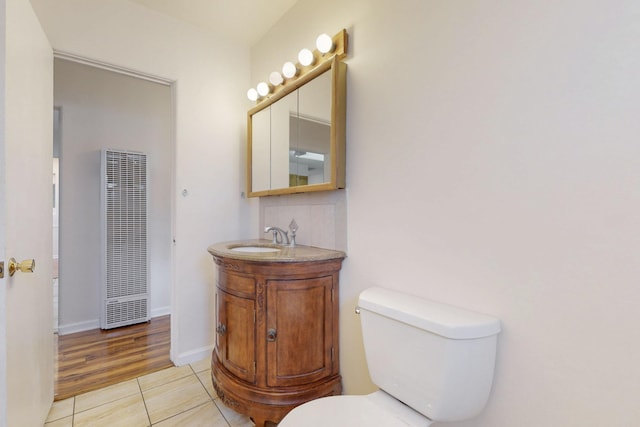 bathroom with toilet, tile patterned flooring, baseboards, a heating unit, and vanity