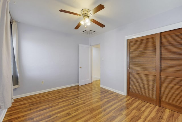 unfurnished bedroom featuring a ceiling fan, wood finished floors, visible vents, baseboards, and a closet