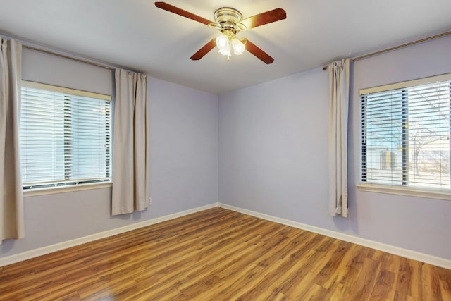 spare room featuring a ceiling fan, wood finished floors, and baseboards