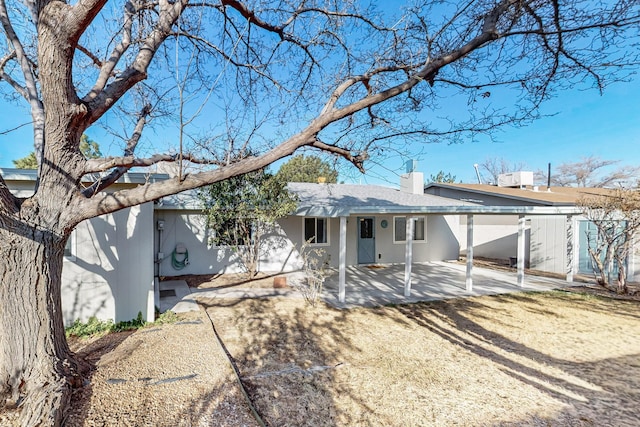 back of house featuring stucco siding, a chimney, and a patio