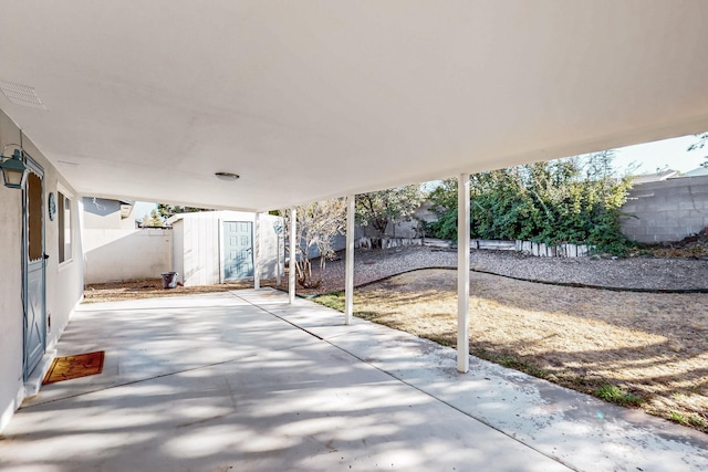 view of patio / terrace featuring visible vents, an outbuilding, a storage shed, and a fenced backyard