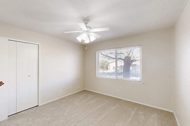 unfurnished bedroom with baseboards, ceiling fan, a closet, a textured ceiling, and carpet flooring