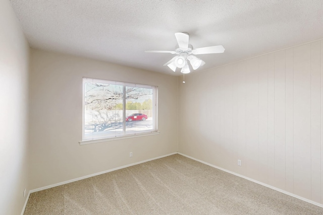 empty room featuring light carpet, baseboards, a textured ceiling, and a ceiling fan