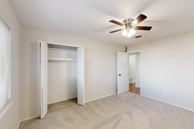 unfurnished bedroom with a closet, visible vents, a ceiling fan, and carpet floors