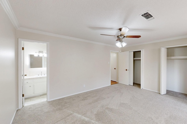 unfurnished bedroom featuring carpet flooring, ornamental molding, visible vents, and multiple closets