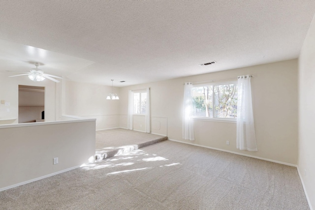 carpeted spare room featuring baseboards, a ceiling fan, visible vents, and a textured ceiling