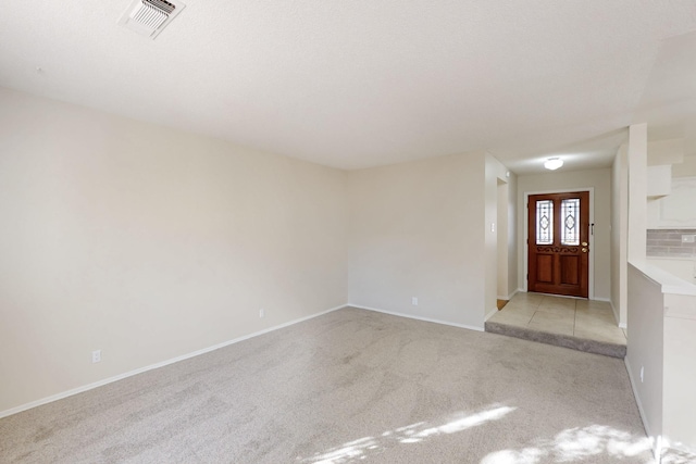 foyer with visible vents, baseboards, and light colored carpet