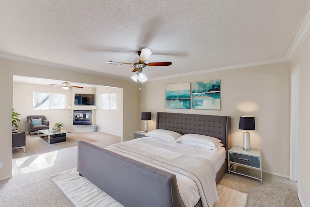 bedroom with a glass covered fireplace, a textured ceiling, carpet, and ornamental molding