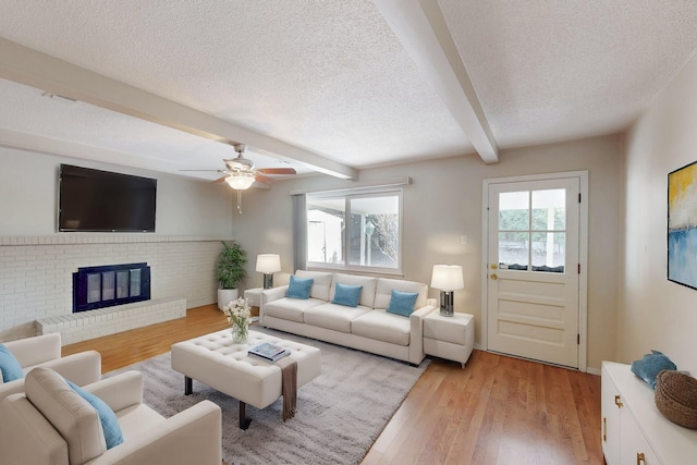 living area with a wealth of natural light, beamed ceiling, a textured ceiling, and light wood-style flooring