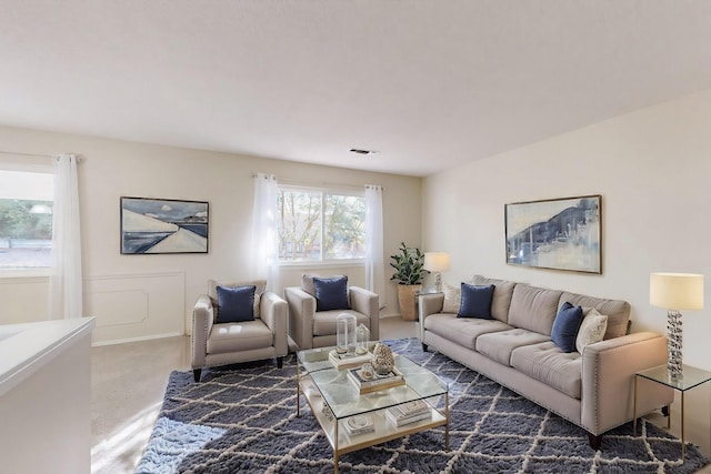 carpeted living room with a decorative wall and visible vents