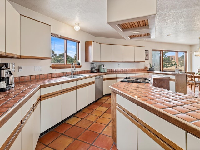 kitchen featuring dishwasher, tile countertops, white cabinets, and a sink