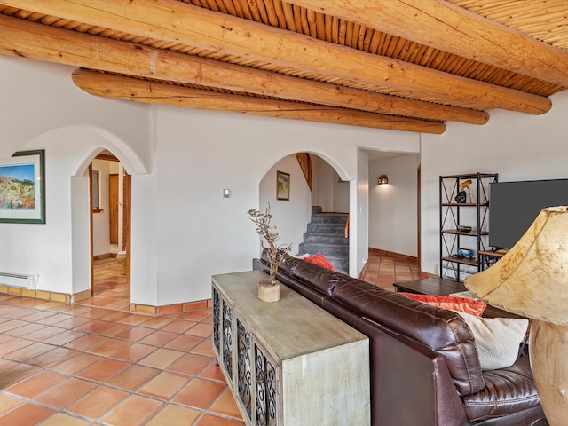 tiled living room featuring beam ceiling, a baseboard heating unit, stairway, arched walkways, and wooden ceiling