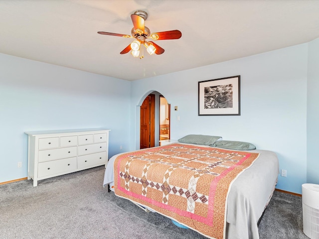 carpeted bedroom with arched walkways, ceiling fan, and baseboards