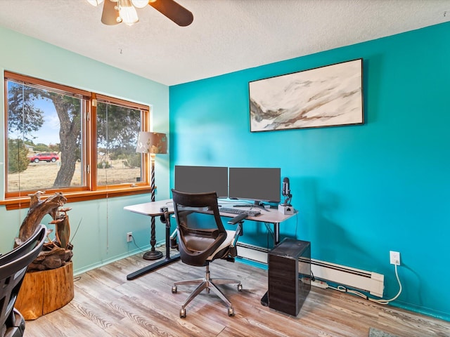 office area with a ceiling fan, wood finished floors, baseboard heating, and a textured ceiling