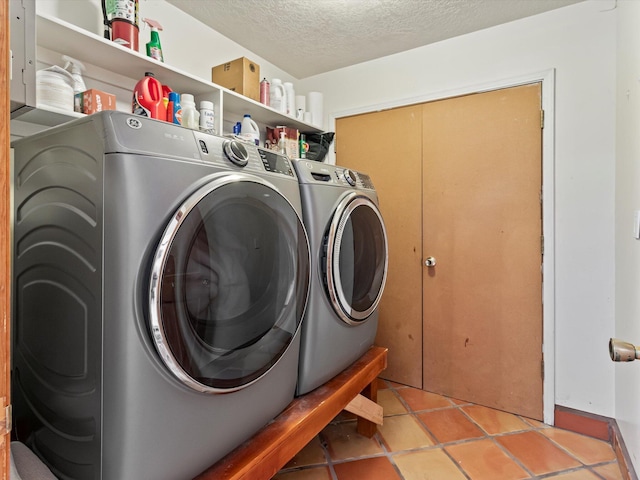 washroom with light tile patterned floors, laundry area, a textured ceiling, and separate washer and dryer