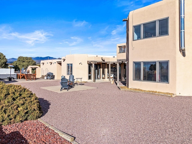 back of house with stucco siding and a patio