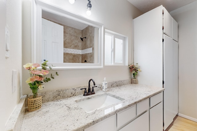 bathroom with walk in shower, wood finished floors, and vanity