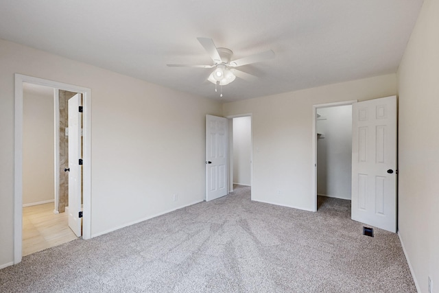 unfurnished bedroom with a walk in closet, ceiling fan, carpet floors, ensuite bathroom, and a closet