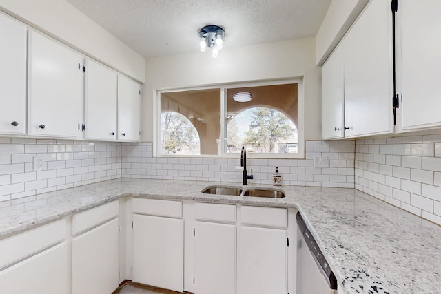 kitchen featuring a sink, tasteful backsplash, dishwasher, and white cabinetry