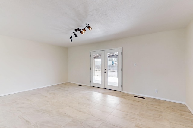 unfurnished room featuring baseboards, french doors, visible vents, and a textured ceiling