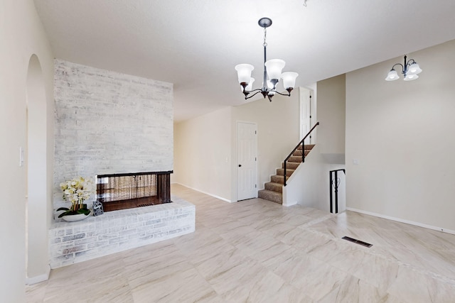 living room featuring visible vents, a notable chandelier, arched walkways, a fireplace, and stairs