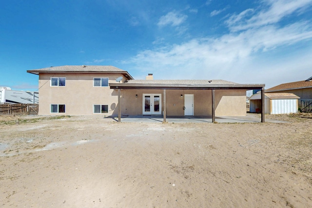 back of house with fence, stucco siding, french doors, a patio area, and a storage unit