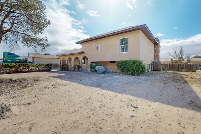 back of property featuring central AC unit, fence, and stucco siding