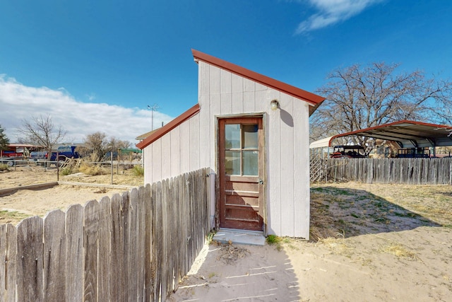 view of shed featuring a carport and fence