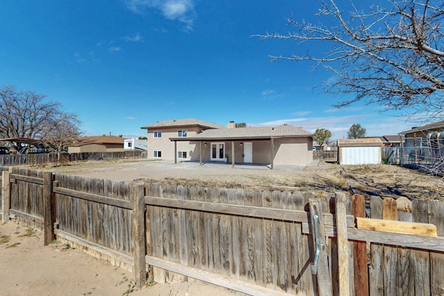 back of house featuring stucco siding, a fenced backyard, and a chimney