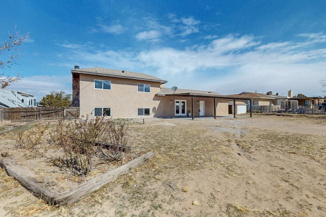 back of house with french doors, a chimney, a fenced backyard, and stucco siding